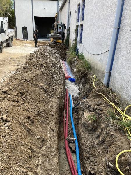 Travaux de viabilisation en cours avec mini-pelle : tranchée équipée des réseaux eau, électricité et télécommunications à Marseille.