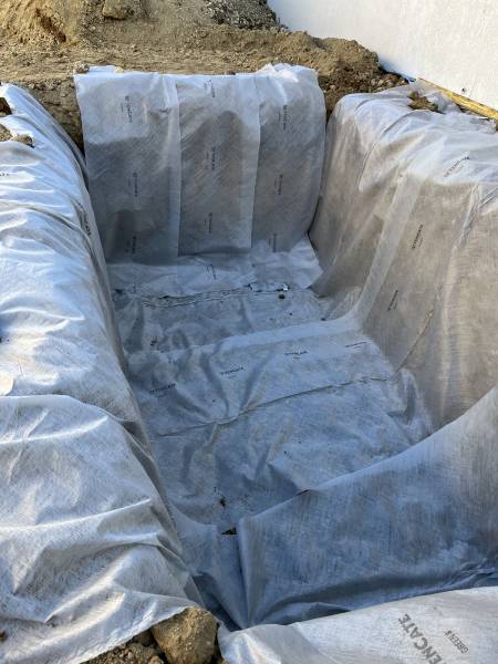 Mise en place complète du géotextile sur fond de fouille avant pose du drainage.