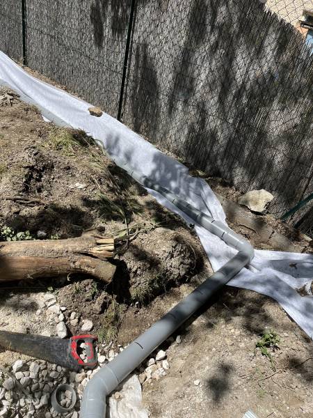 Drain rigide fendu en cours de pose, ajusté en courbe sur un terrain en pente.
